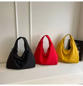 Detailed view of large crescent tote bags in black, red, and yellow on marble surface