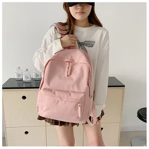 Pink minimalist backpack featuring woven knot zippers and a spacious front pocket design