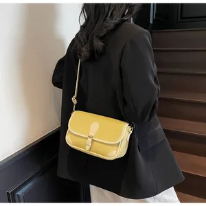 Gros plan d'un sac à bandoulière en cuir jaune porté par un mannequin en blazer noir
