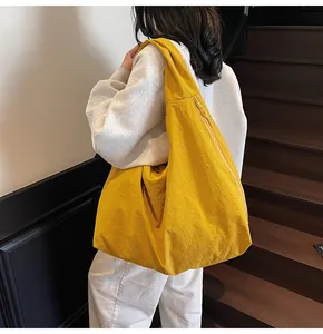 Bright yellow large tote bag with pleated texture shown on a shoulder in a stair setting