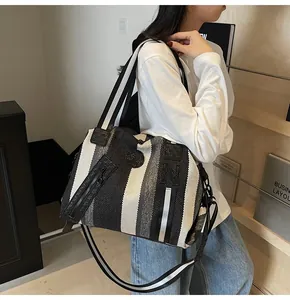 Detail showing high-capacity striped woven shoulder bag with durable leather handles