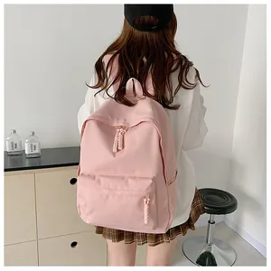 Rear view of a minimalist pink backpack featuring woven rope zippers on a model