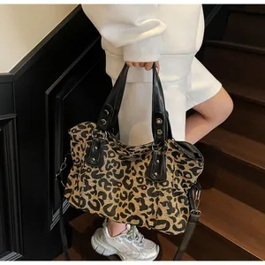 Close-up of leopard print tote bag with black leather straps and metal rivet details