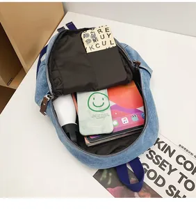 Top view of open blue denim backpack showing spacious main compartment with daily essentials