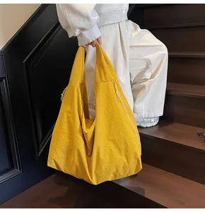 Detail of bright yellow large tote bag with pleated nylon texture and shoulder strap