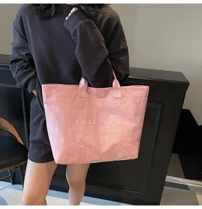 Pink glossy tote bag with TOTE BAG lettering shown on model for a trendy commute look