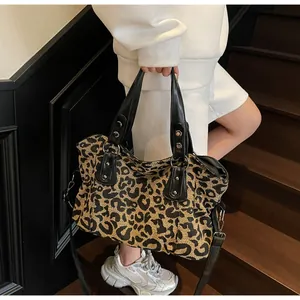 Detail of leopard print canvas bag with black leather handles and silver rivet accents