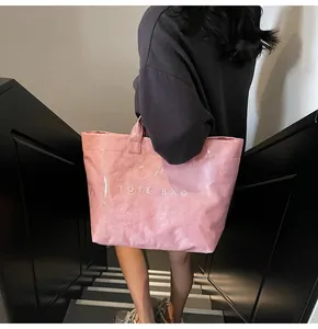 Pink tote bag with TOTE BAG lettering shown on person in a street style setting