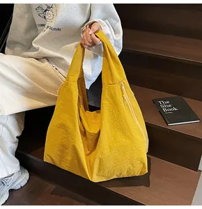 Macro view of bright yellow tote bag showing crinkled nylon texture and wide shoulder strap