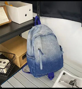 Détail du sac à dos en jean dégradé avec poche zippée verticale et texture en toile