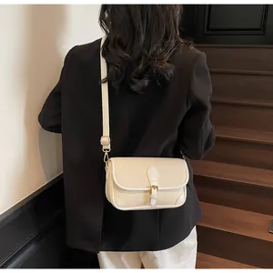 Détail d'un sac bandoulière beige en cuir grainé avec d'élégantes ferrures dorées