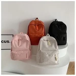 Minimalist nylon school backpacks in pink, orange, beige, and black with woven zip pulls
