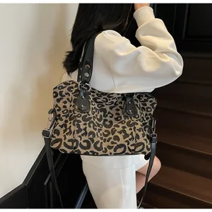 Detail view of large leopard print tote bag with black leather handles and shoulder strap