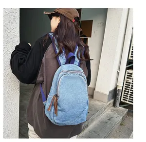 Detail of vintage washed denim backpack with blue fabric straps and leather zip pulls