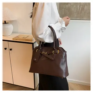 Vue détaillée du sac cabas en cuir marron foncé avec boucle mors dorée et poignées solides
