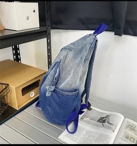 Vue détaillée du sac à dos en denim dégradé avec des tirettes de fermeture à franges