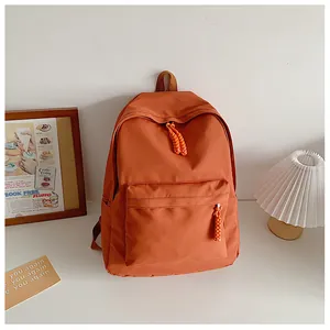 Detail of orange nylon backpack with braided zipper pull and spacious front pocket