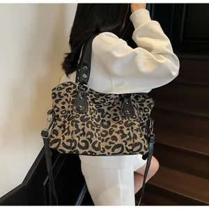 Detail shot of leopard print canvas tote bag with black leather handles and silver studs