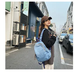 Outdoor street view of a woman wearing the light blue denim backpack with zipper details