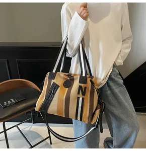 Detail of striped travel tote showing the front zipper pocket and decorative N patch