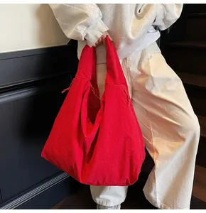 Detail of red oversized nylon tote bag with drawstring side and wide shoulder strap