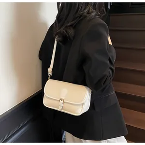 Gros plan d'un sac bandoulière beige texture litchi porté par un mannequin en costume noir