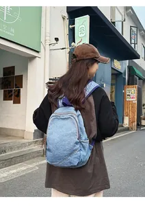 Rear view of a light blue denim backpack with front pocket in a vintage street style