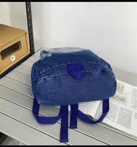 Vue détaillée du dos et de la base d'un sac à dos en jean bleu avec bretelles