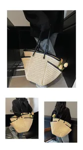 Detail of large woven straw tote bag with black leather handles and side pocket