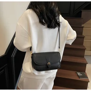Gros plan d'un sac bandoulière en cuir grainé noir avec boucle dorée et rabat chic