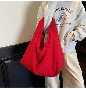 Side view of red large capacity nylon tote bag worn by a model in casual style