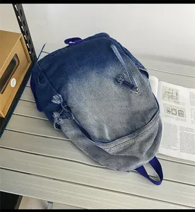 Détail du sac à dos en denim délavé avec dégradé de bleu et fermetures à franges