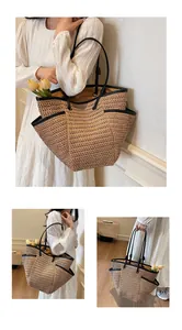 Detail of straw tote bag showing black leather handles and functional side pockets