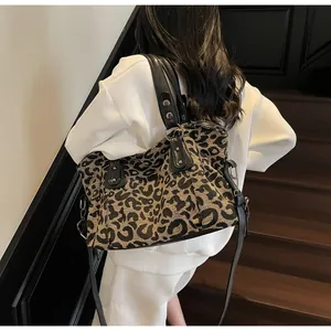 Close-up of leopard print tote bag featuring black leather handles and silver metal rivets