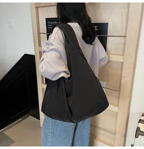 Side view of large black nylon tote bag showing soft texture and slouchy design on model