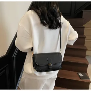 Détail d'un sac bandoulière noir en cuir grainé avec boucle dorée porté par un mannequin