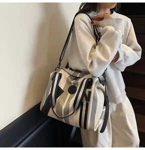 Close-up of striped canvas tote bag with black circular logo and detachable shoulder strap