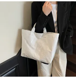 Close-up of a white textured tote bag with embossed lettering and large capacity