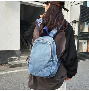 Back view of a casual light blue washed denim backpack worn on a city street