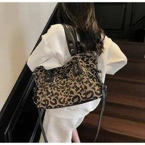 Leopard print tote bag with black handles and metal studs shown on a model