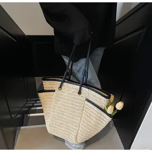 Close-up of large woven straw tote bag with black leather trim and tulip detail