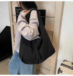 Detail of a large black nylon tote bag shown on a model for everyday commute style