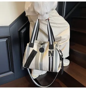 Close-up of striped canvas tote bag showing zipper detail and black 'N' patch