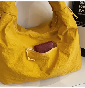 Detail of a ginger yellow hobo bag showing wrinkled fabric texture and front zipper pocket