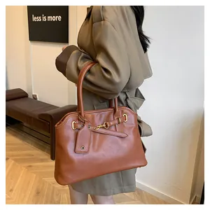 Détail du sac cabas en cuir caramel avec boucle dorée et finitions de bandoulière