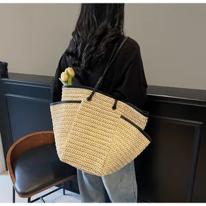 Close-up of the woven texture and black leather strap on a large straw tote bag