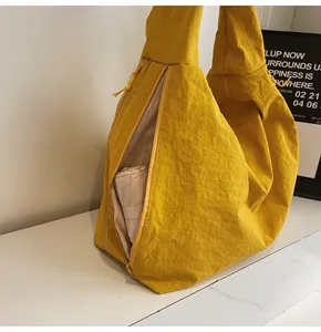 Macro detail of bright yellow nylon tote bag with fine wrinkled texture and zip closure