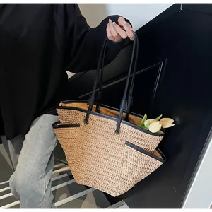 Detail of woven straw tote bag featuring contrast black trim and side functional pocket