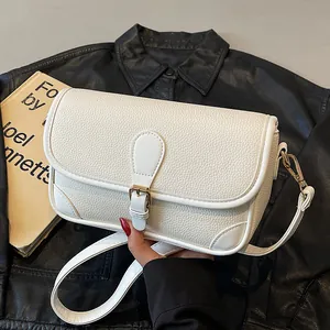 Sac bandoulière blanc chic en cuir grainé avec boucle dorée sur une veste en cuir