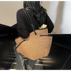 Detail view of woven straw tote bag with black leather straps and functional side pocket